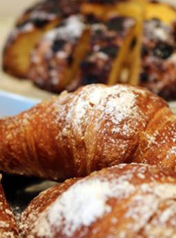 Croissant con zucchero a velo e dolce farcito sullo sfondo.