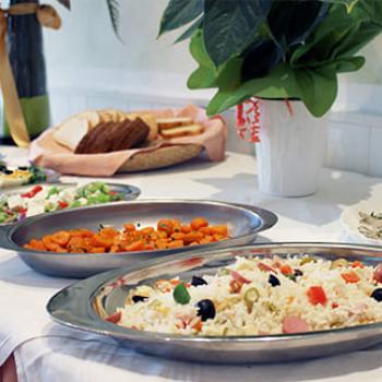 Buffet con riso, verdure, pane e piatti vari su un tavolo decorato.