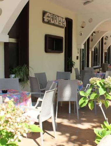 Terrazza con tavoli colorati e piante, ambiente accogliente e rilassante.