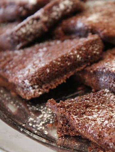 Brownies al cioccolato con zucchero a velo, serviti su un piatto d'argento.